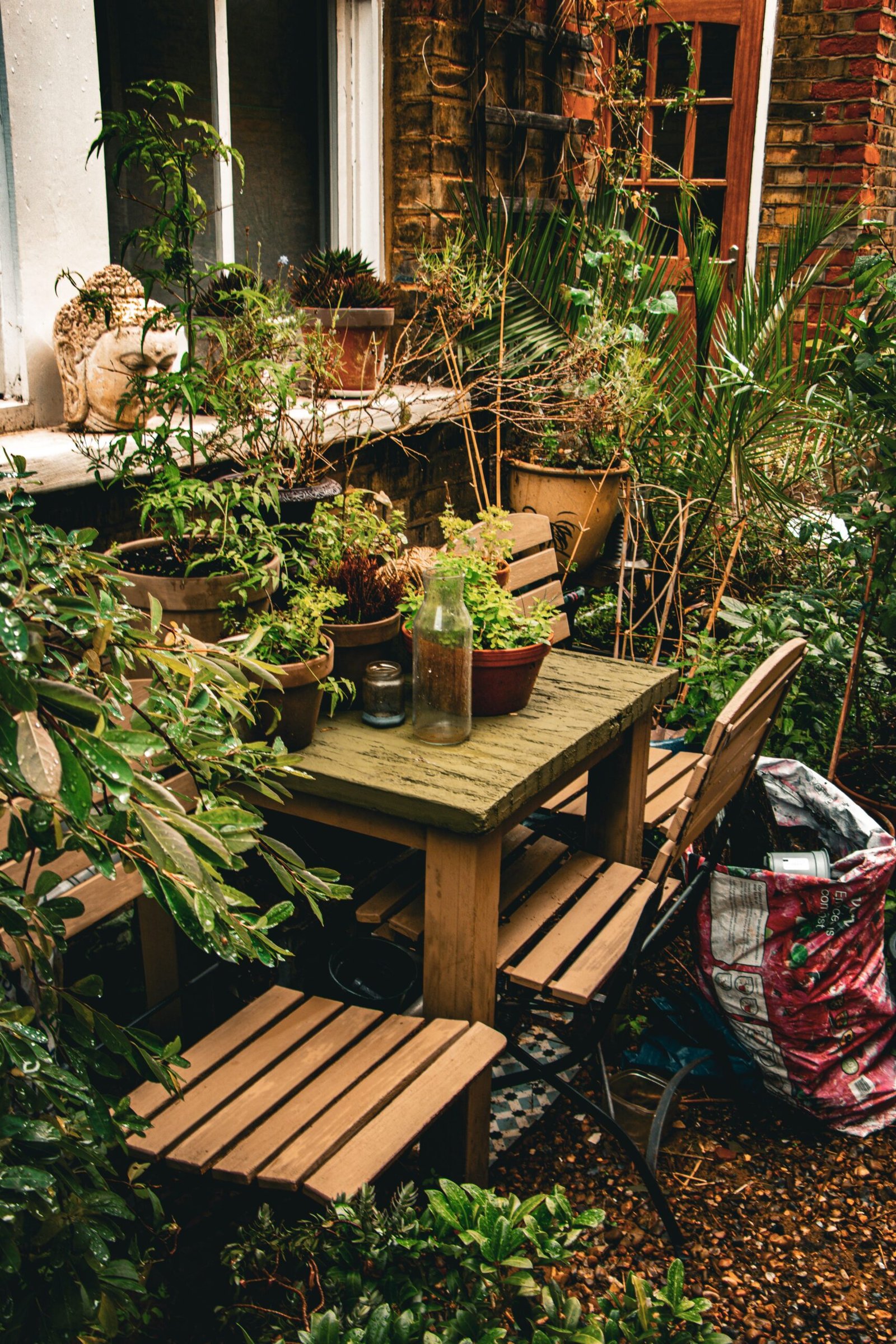 Small garden with a bistro table and chairs surrounded by pots and container plants, showing how food and flowers can be grown in a limited space.